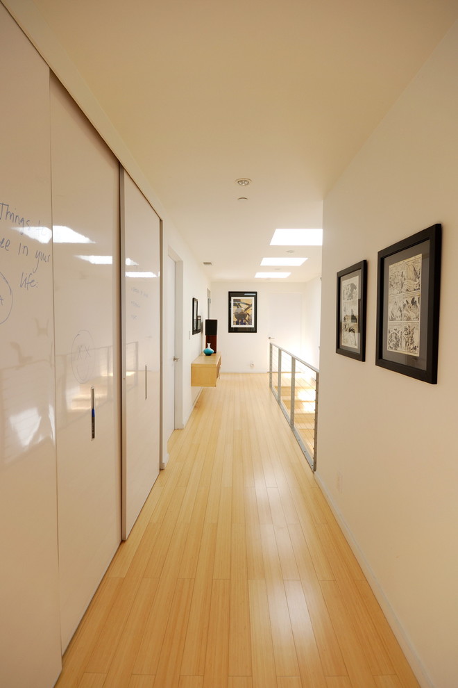 Ejemplo de recibidores y pasillos minimalistas con suelo de madera clara, paredes blancas y suelo amarillo