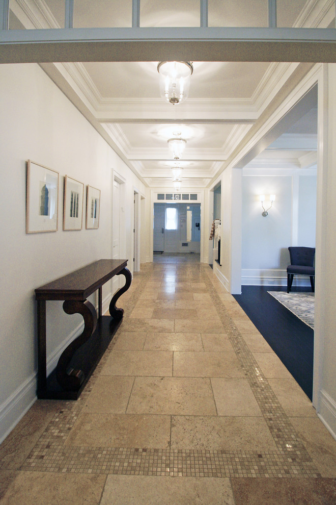 Aménagement d'un grand couloir classique avec un mur blanc, un sol en travertin et un sol beige.