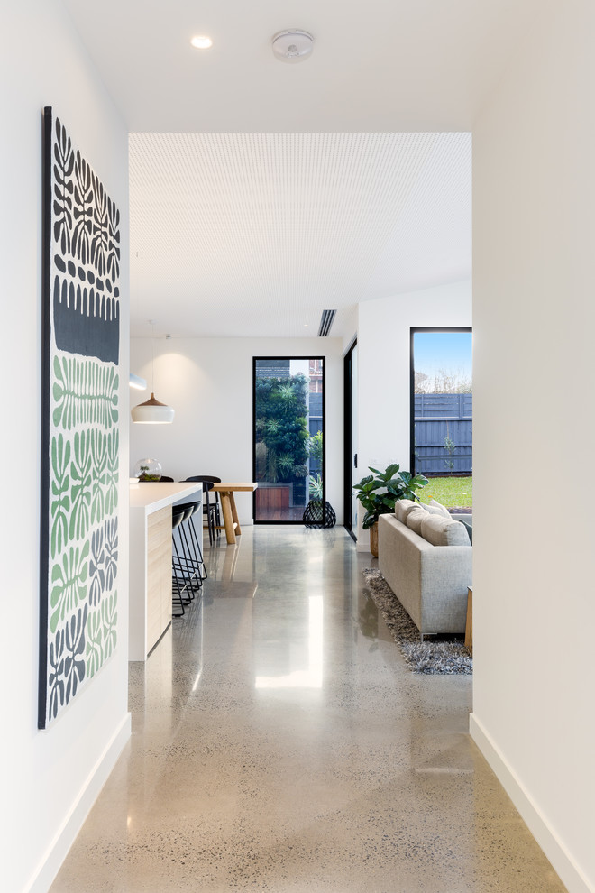 Idée de décoration pour un couloir design avec un mur blanc et sol en béton ciré.