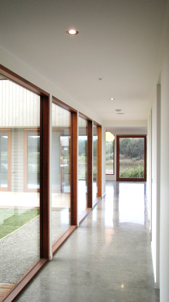 Réalisation d'un couloir design de taille moyenne avec un mur blanc et sol en béton ciré.