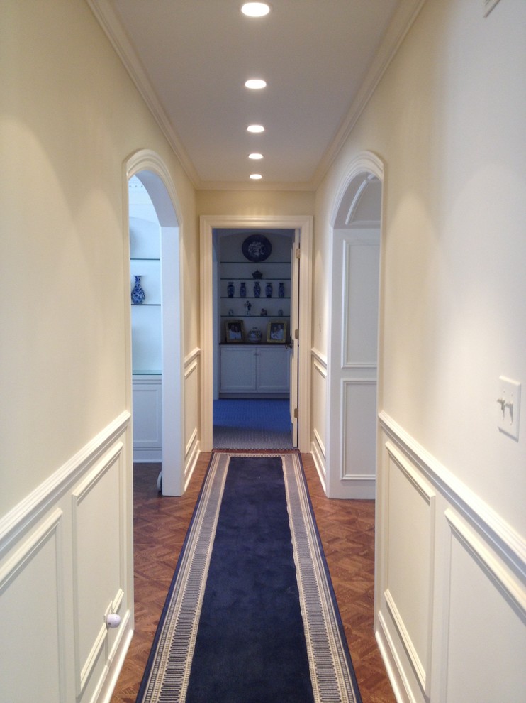 Exemple d'un couloir chic de taille moyenne avec un mur blanc et un sol en bois brun.