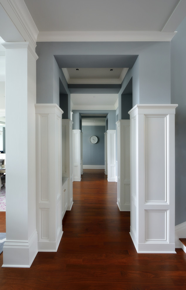 На фото: большой коридор в стиле неоклассика (современная классика) с синими стенами, темным паркетным полом и коричневым полом с