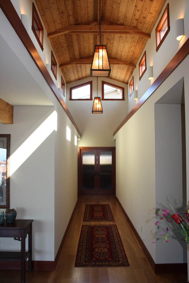 Inspiration pour un grand couloir craftsman avec un mur blanc, un sol en bois brun et un sol marron.