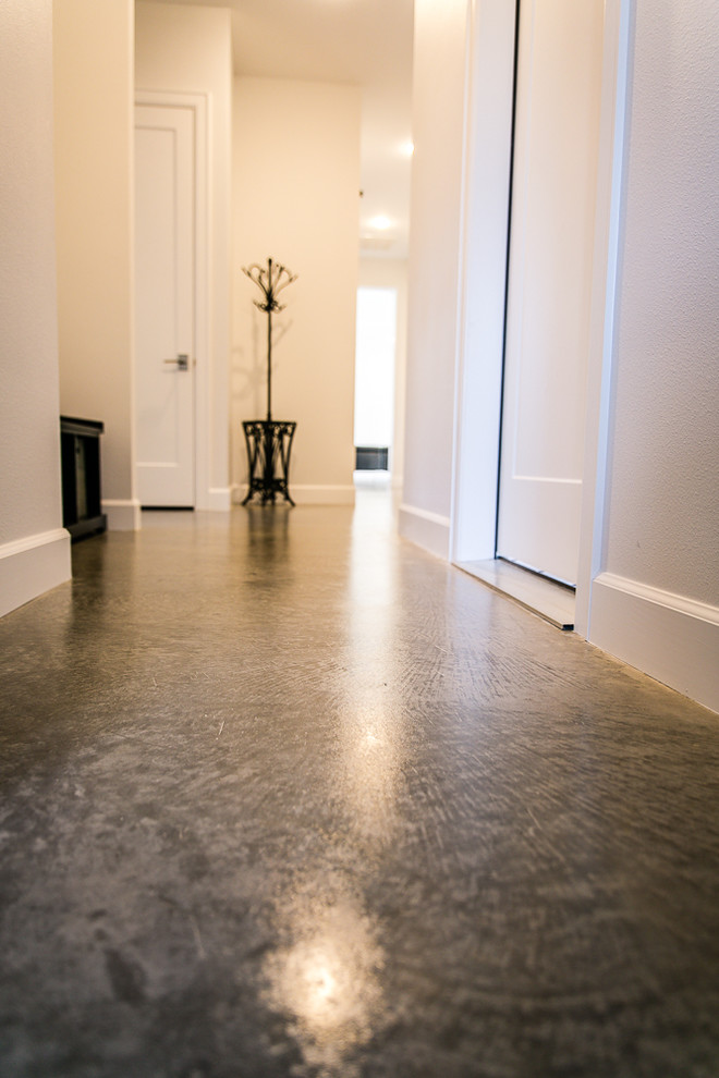 Cette photo montre un couloir tendance de taille moyenne avec un mur blanc, sol en béton ciré et un sol gris.