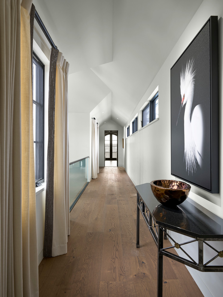На фото: огромный, узкий коридор в современном стиле с белыми стенами и паркетным полом среднего тона с