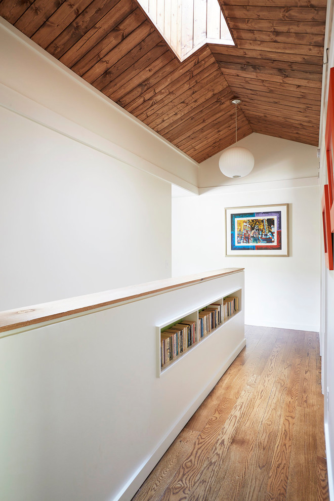 Ispirazione per un ingresso o corridoio moderno con pareti bianche, pavimento in legno massello medio e pavimento marrone