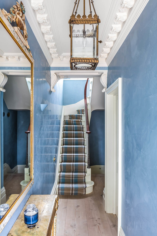 Exempel på en liten klassisk hall, med blå väggar, ljust trägolv och brunt golv