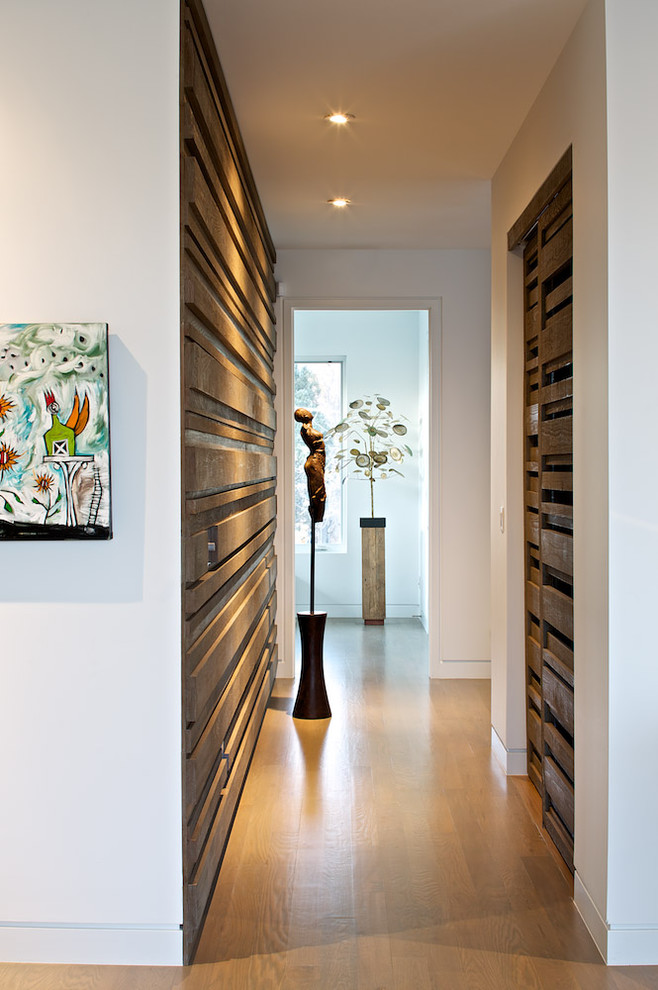 Esempio di un ingresso o corridoio minimalista con pareti bianche e pavimento in legno massello medio