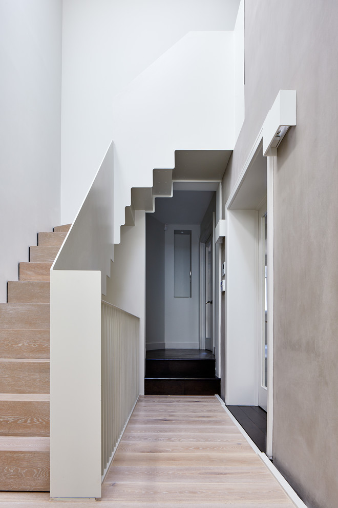 Diseño de recibidores y pasillos minimalistas grandes con paredes grises y suelo de madera clara