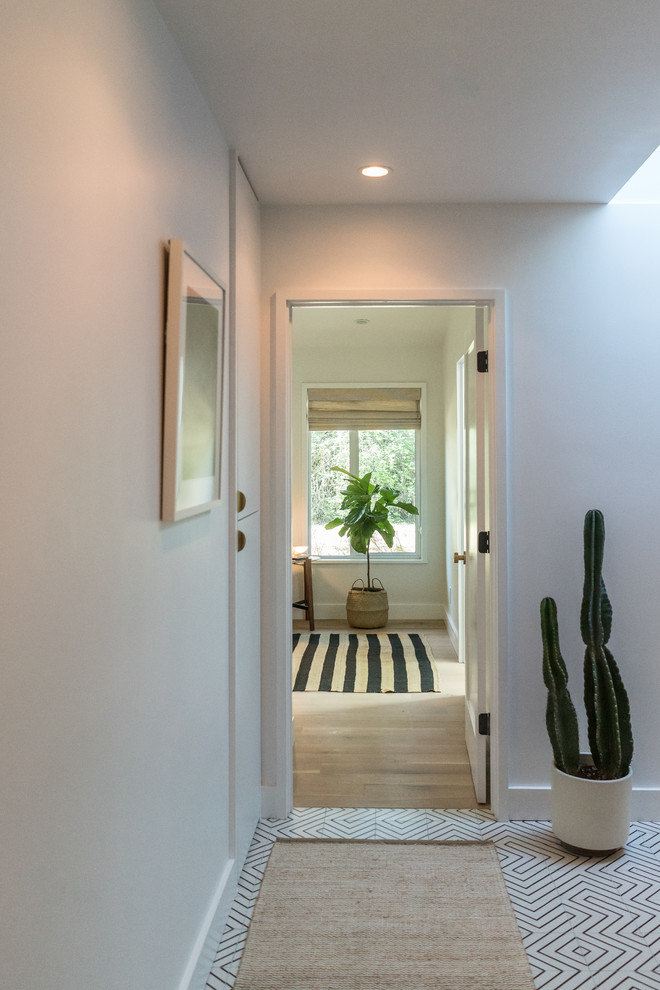 Cette photo montre un couloir tendance de taille moyenne avec un mur blanc, parquet clair et un sol beige.