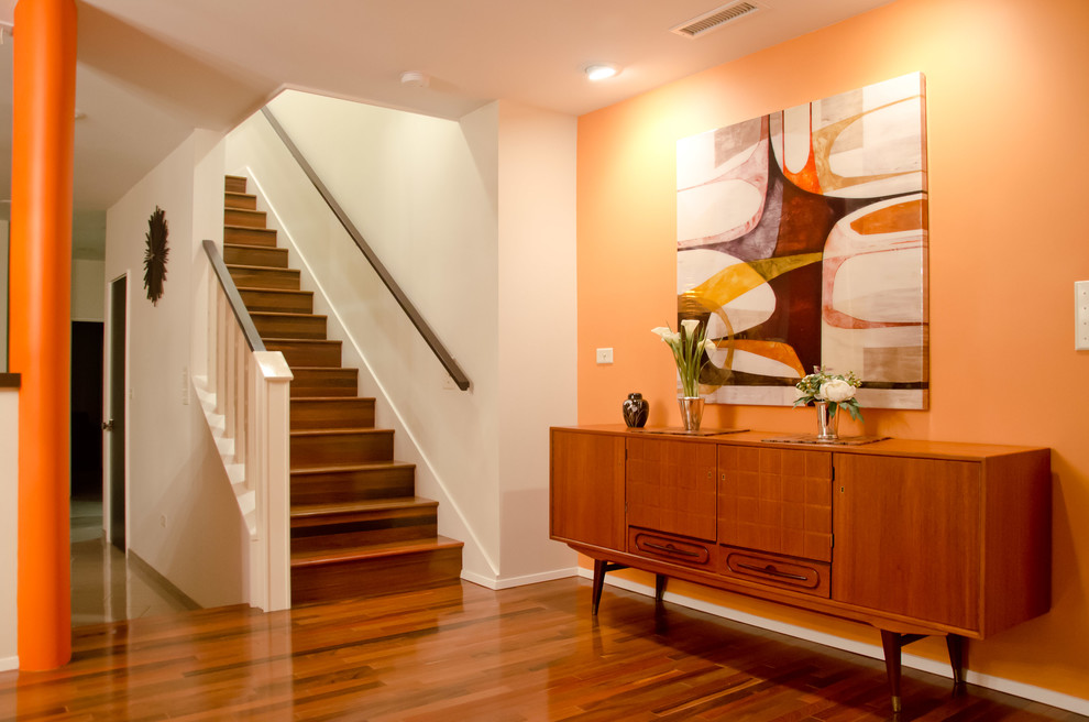 Foto di un ingresso o corridoio minimalista con pareti arancioni, pavimento in legno massello medio e pavimento arancione