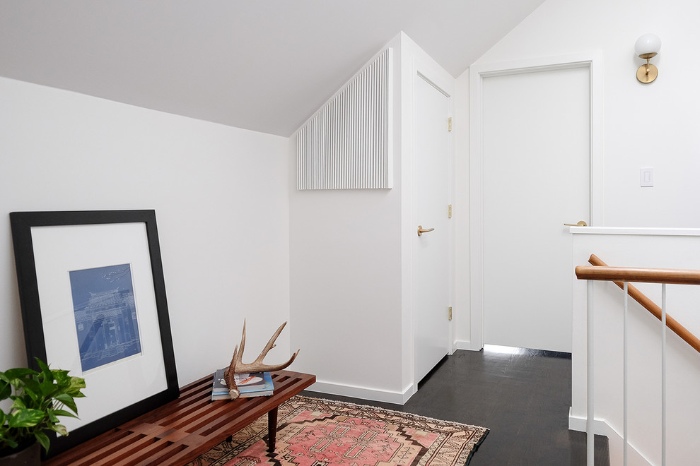Cette image montre un couloir vintage avec un mur blanc, parquet foncé et un sol noir.