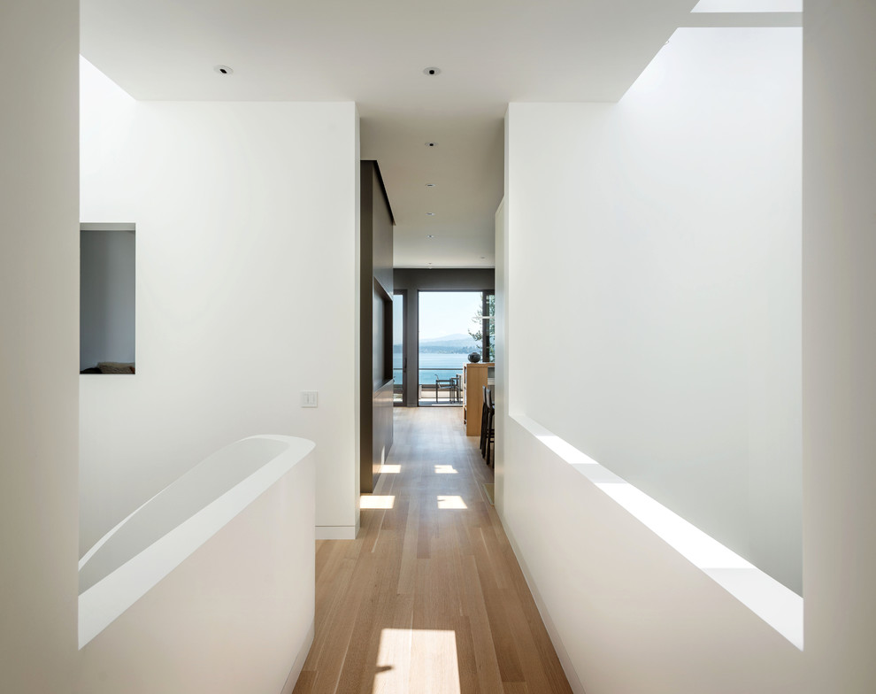 Hallway - mid-sized modern light wood floor hallway idea in Seattle with white walls