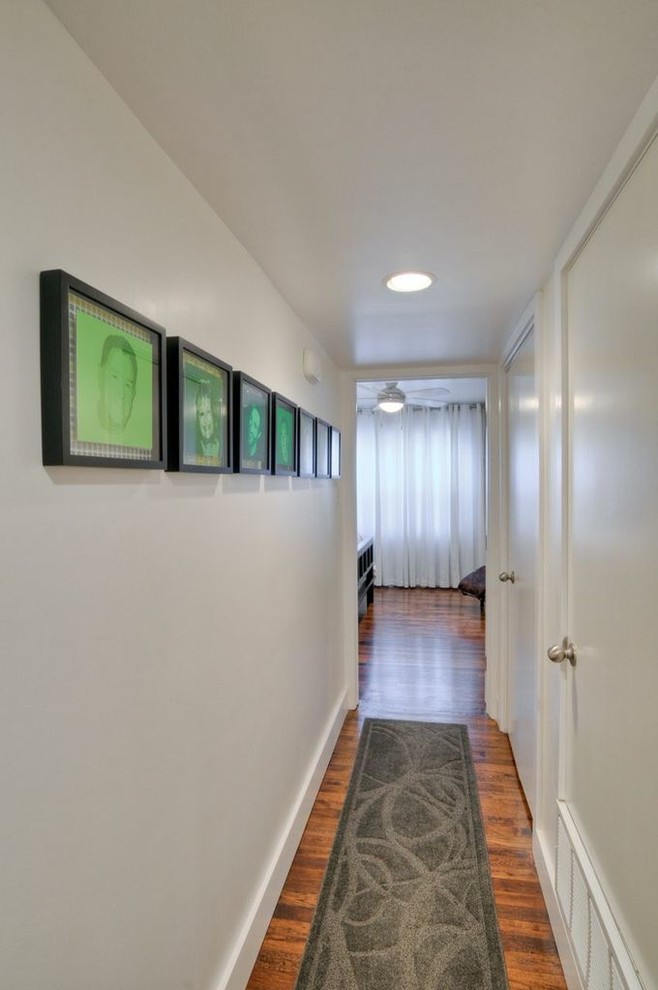 Idée de décoration pour un petit couloir minimaliste avec un mur blanc et un sol en bois brun.