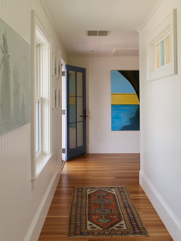 Exemple d'un couloir chic de taille moyenne avec un mur blanc et un sol en bois brun.