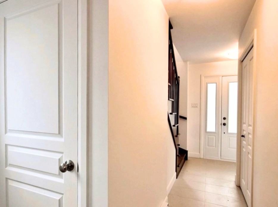 Cette image montre un couloir design de taille moyenne avec un mur blanc, un sol en carrelage de céramique et un sol beige.