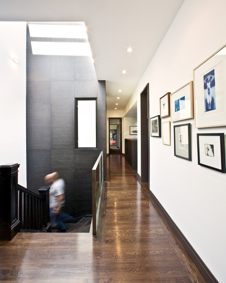 Idée de décoration pour un couloir design avec un mur blanc et parquet foncé.