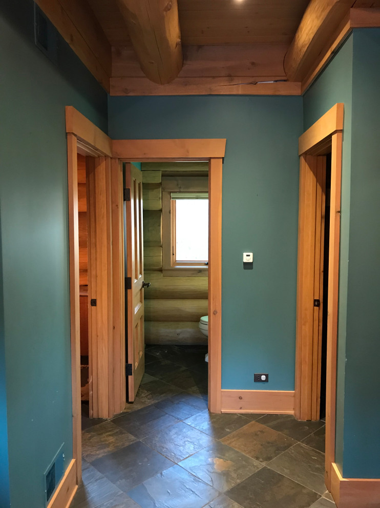 Ispirazione per un ingresso o corridoio classico di medie dimensioni con pareti verdi, pavimento in ardesia, pavimento marrone, pareti in legno e travi a vista