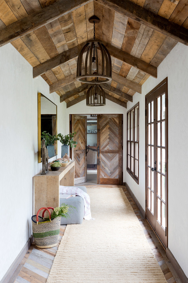 Exemple d'un couloir nature avec un mur blanc, un sol en bois brun et un sol multicolore.