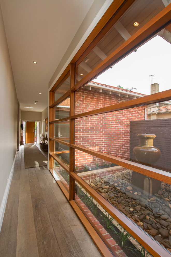 Réalisation d'un couloir design avec un mur beige et un sol en bois brun.