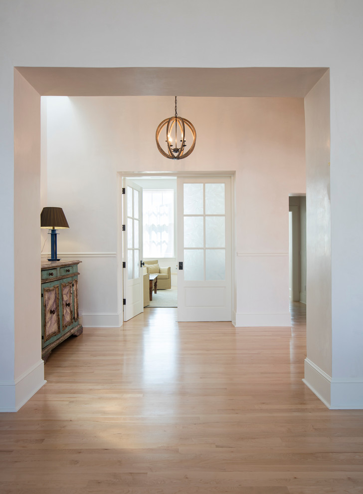 Mid-sized elegant light wood floor hallway photo in Albuquerque with white walls