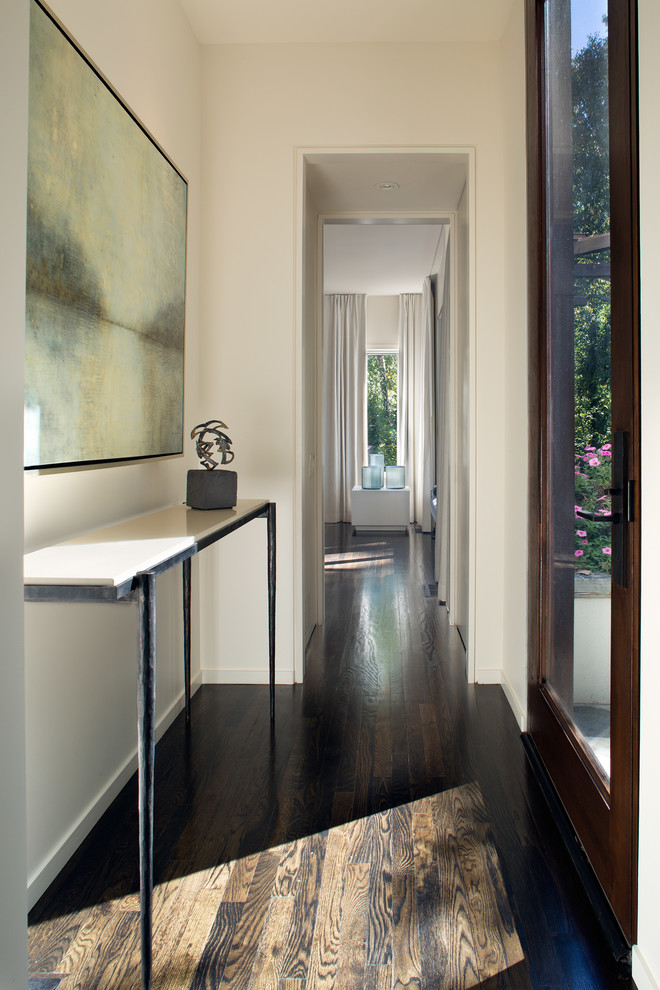 Ispirazione per un grande ingresso o corridoio minimalista con pareti beige, parquet scuro e pavimento marrone