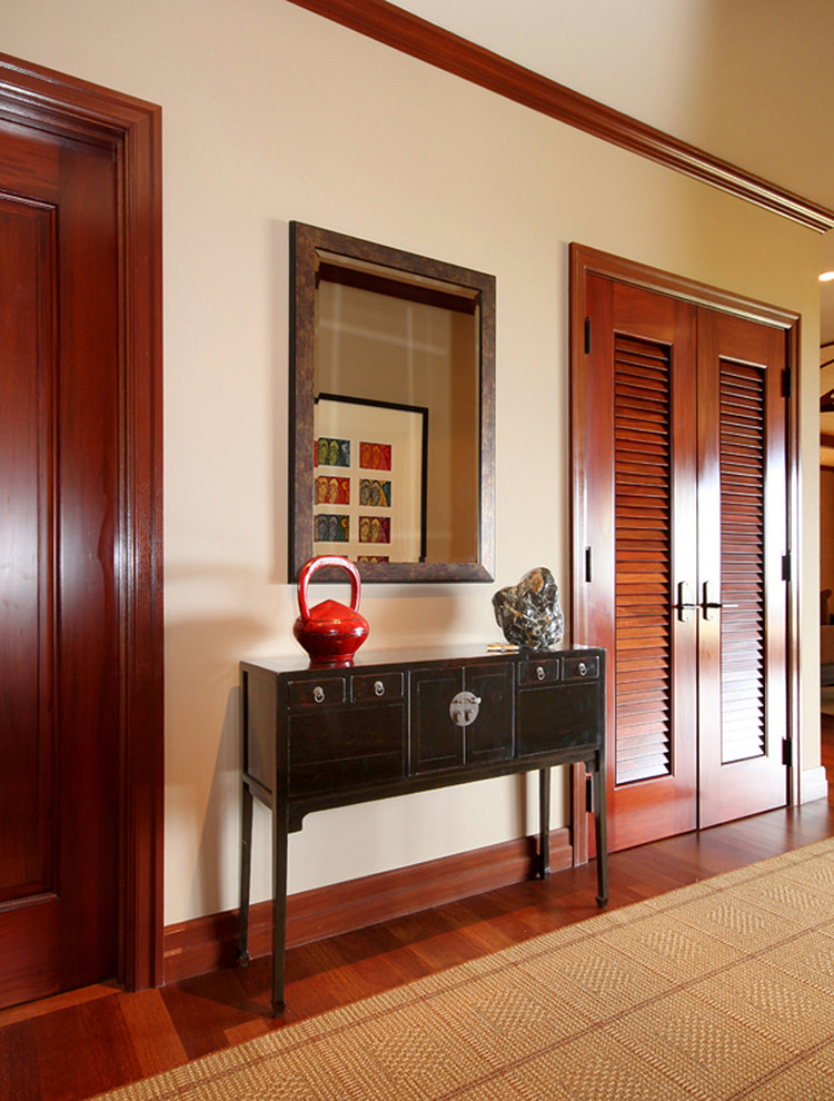 Aménagement d'un couloir exotique de taille moyenne avec un mur beige, un sol en bois brun et un sol rouge.