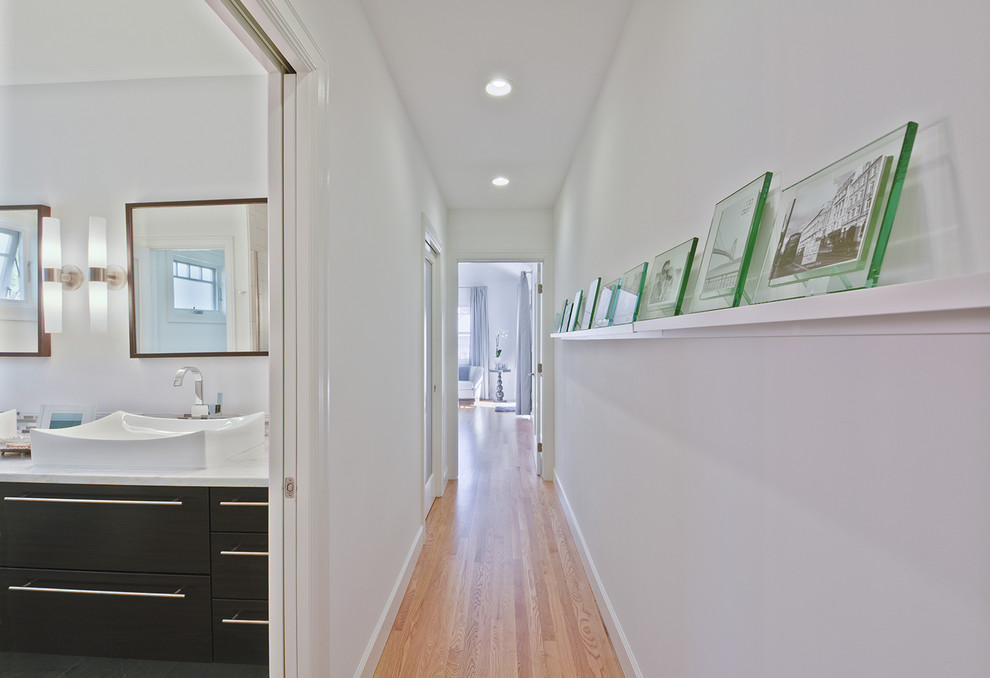 Inspiration for a large modern light wood floor hallway remodel in Columbus with white walls