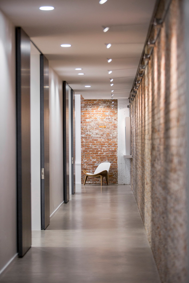 Пример оригинального дизайна: большой, узкий коридор в стиле лофт с белыми стенами, бетонным полом и серым полом