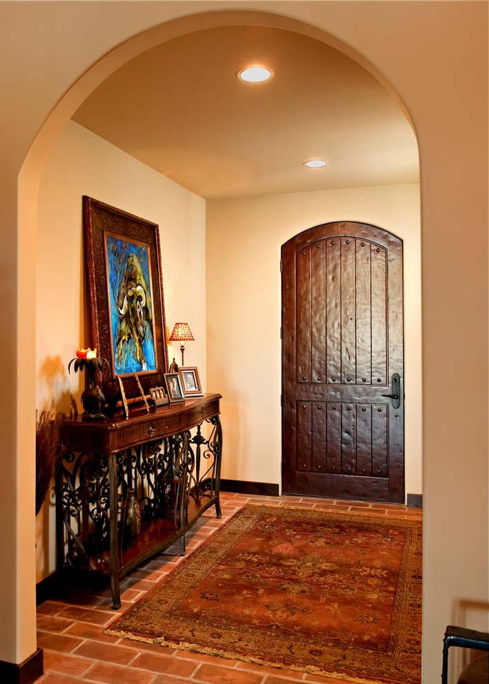 Hallway - small mediterranean brick floor hallway idea in Los Angeles with beige walls