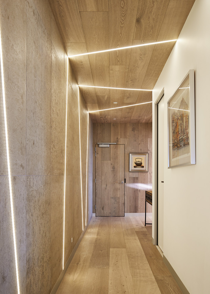 Inspiration pour un couloir design de taille moyenne avec un mur blanc, un sol en bois brun et un sol marron.