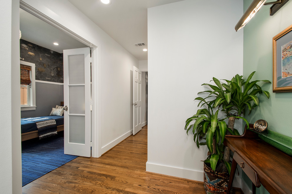 Hallway - mid-sized eclectic medium tone wood floor hallway idea in Dallas with white walls