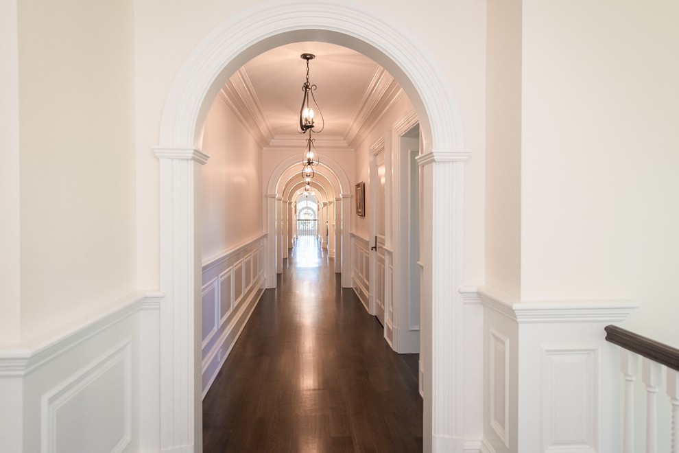 Стильный дизайн: огромный коридор в классическом стиле с белыми стенами и темным паркетным полом - последний тренд