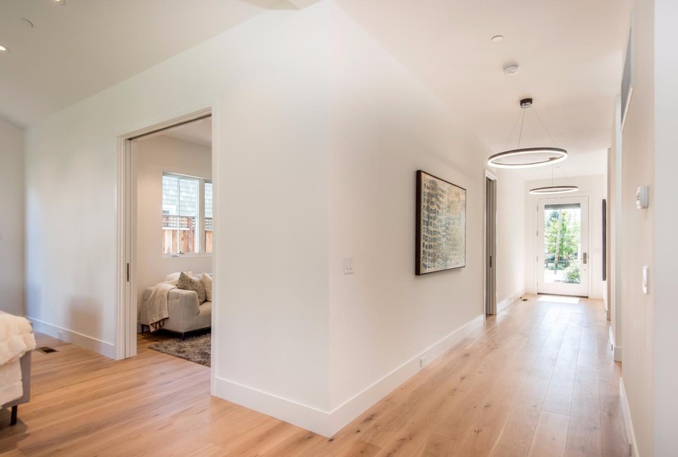 Example of a large minimalist light wood floor and beige floor hallway design in San Francisco with white walls