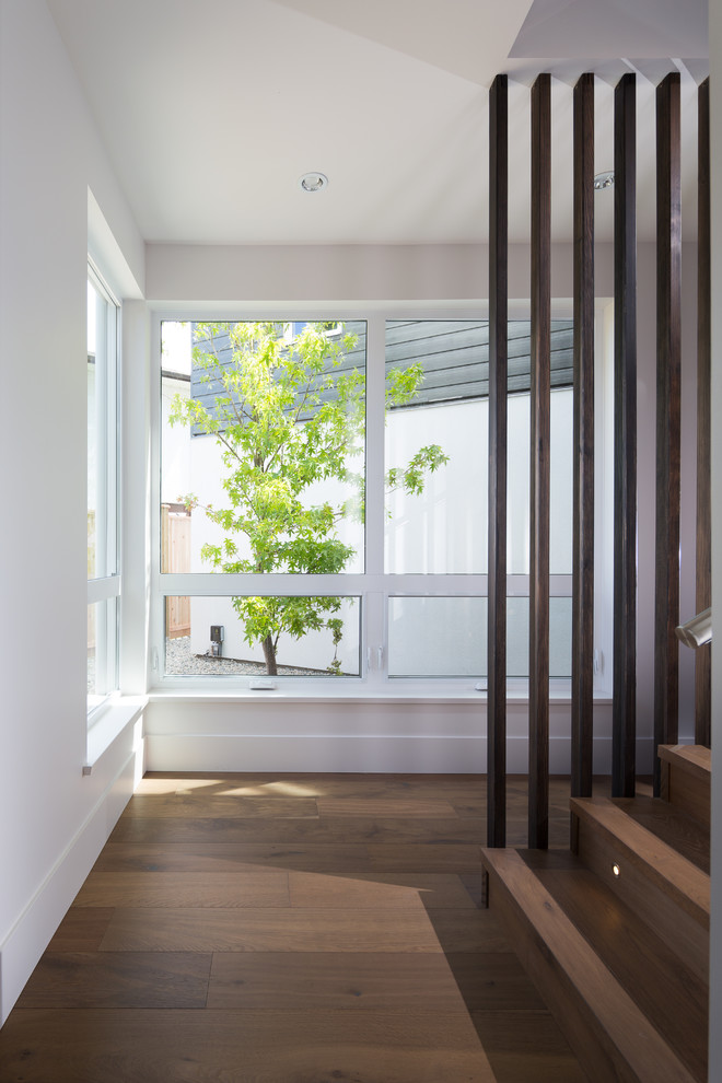Ispirazione per un ingresso o corridoio moderno di medie dimensioni con pareti bianche e pavimento in legno massello medio