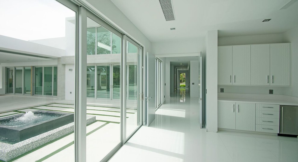 Aménagement d'un très grand couloir moderne avec un mur blanc, un sol en carrelage de porcelaine et un sol blanc.
