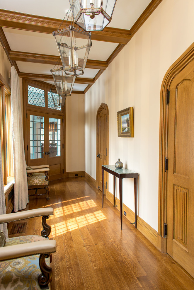 Diseño de recibidores y pasillos clásicos con paredes blancas, suelo de madera en tonos medios y suelo marrón