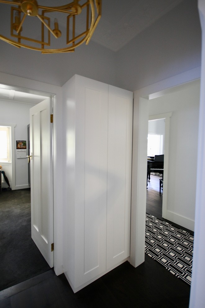 シドニーにあるお手頃価格の小さなトランジショナルスタイルのおしゃれな廊下 (カーペット敷き、黒い床、白い壁) の写真