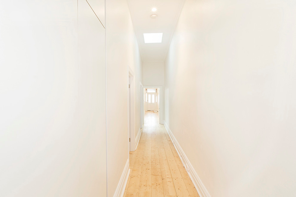 Foto di un piccolo ingresso o corridoio contemporaneo con pareti bianche, parquet chiaro e pavimento beige