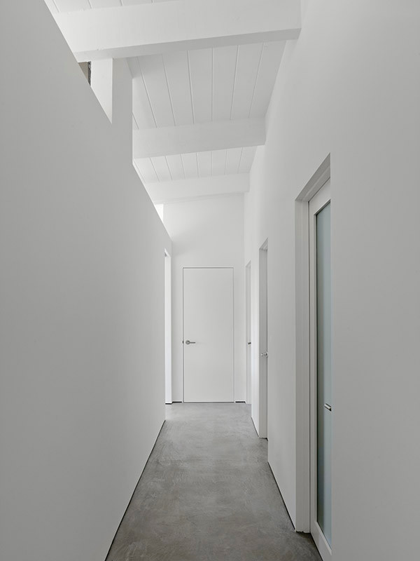 Modern inredning av en mellanstor hall, med vita väggar och betonggolv