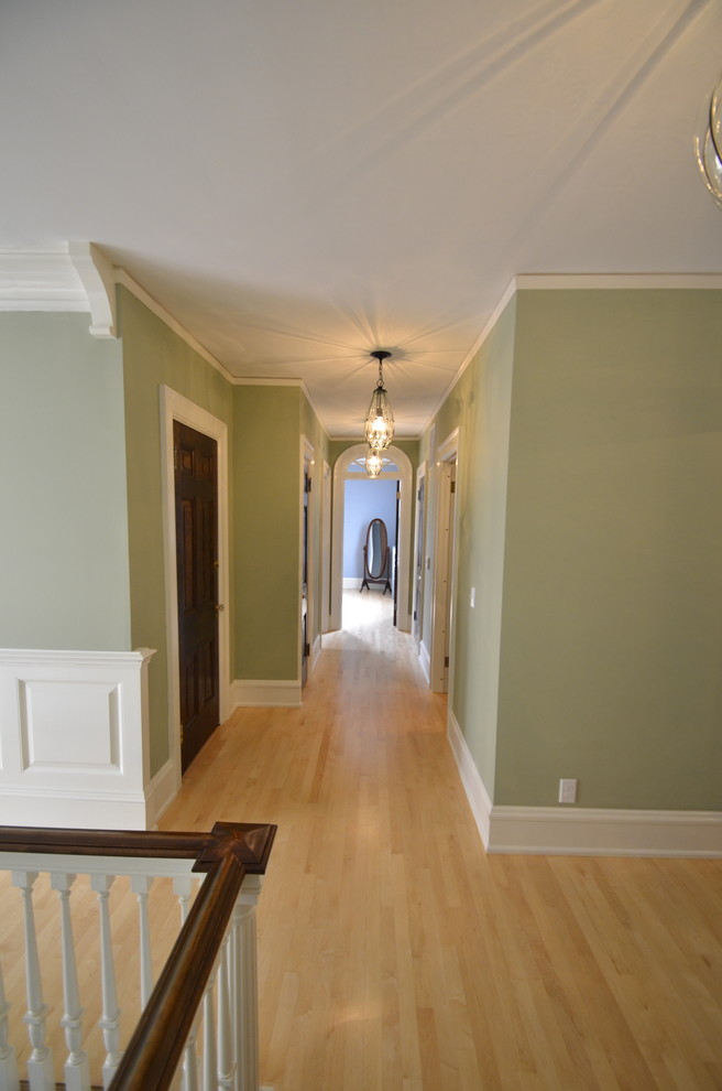 На фото: коридор в классическом стиле с зелеными стенами и светлым паркетным полом с