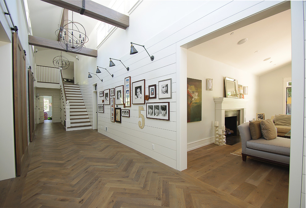На фото: большой коридор в стиле кантри с белыми стенами, паркетным полом среднего тона и коричневым полом с