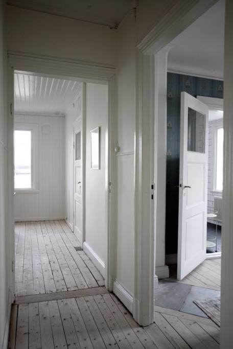 Foto på en lantlig hall, med vita väggar, ljust trägolv och beiget golv