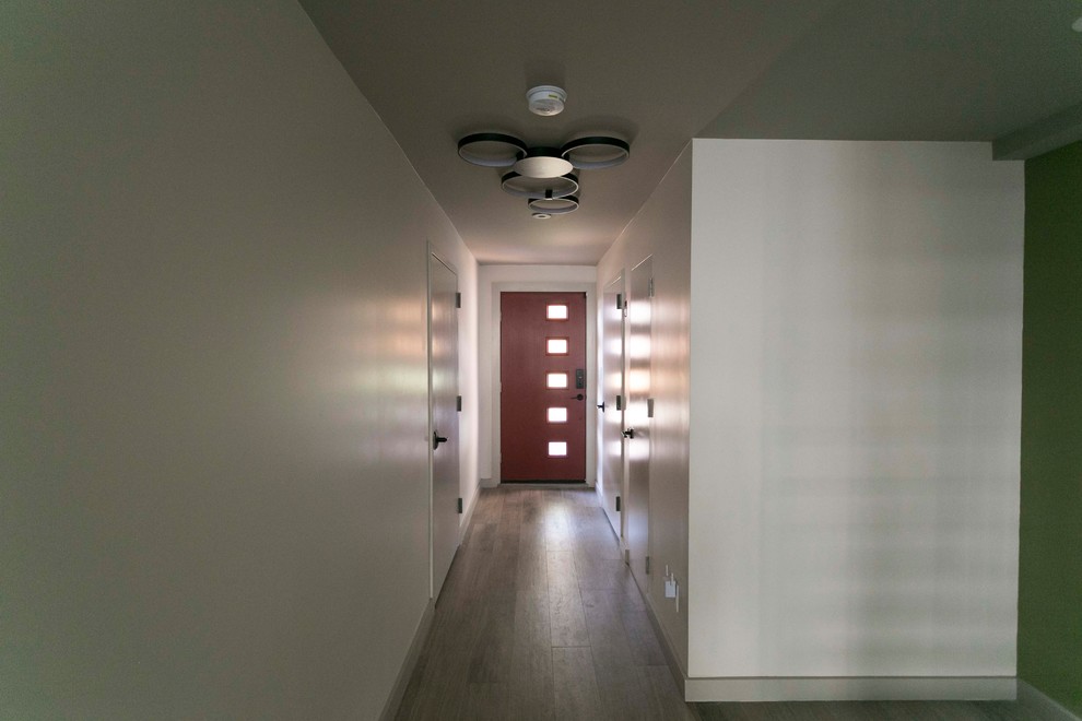 Exemple d'un grand couloir rétro avec un mur blanc, un sol en bois brun et un sol marron.