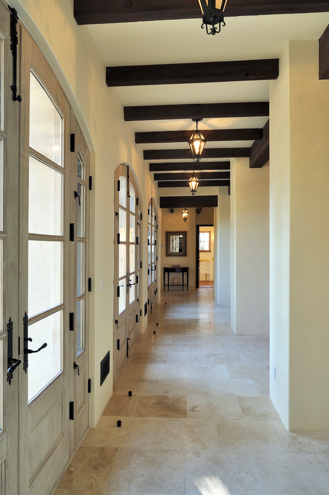 Cette image montre un grand couloir traditionnel avec un mur blanc et un sol en travertin.