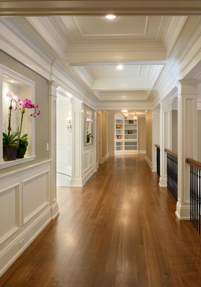 Hallway - large transitional medium tone wood floor hallway idea in Boston with white walls