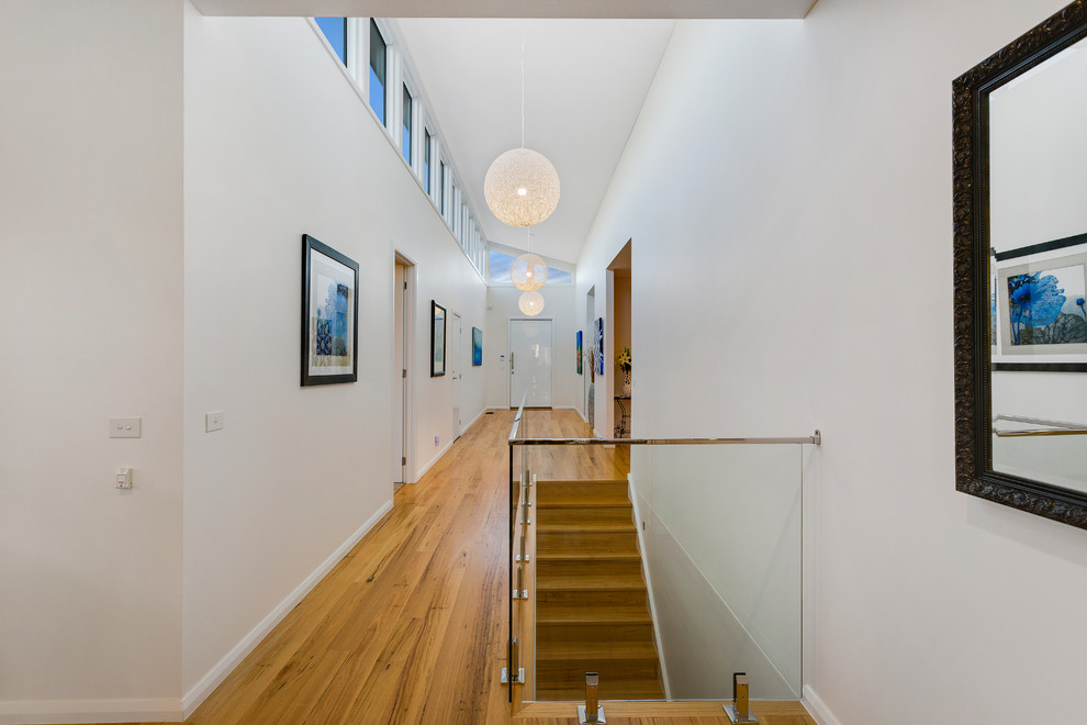 Пример оригинального дизайна: большой коридор в современном стиле с белыми стенами, светлым паркетным полом и коричневым полом