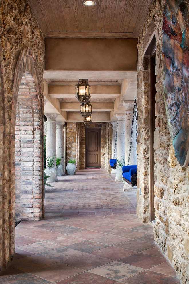 На фото: огромный коридор в средиземноморском стиле с бежевыми стенами, коричневым полом и полом из терракотовой плитки с