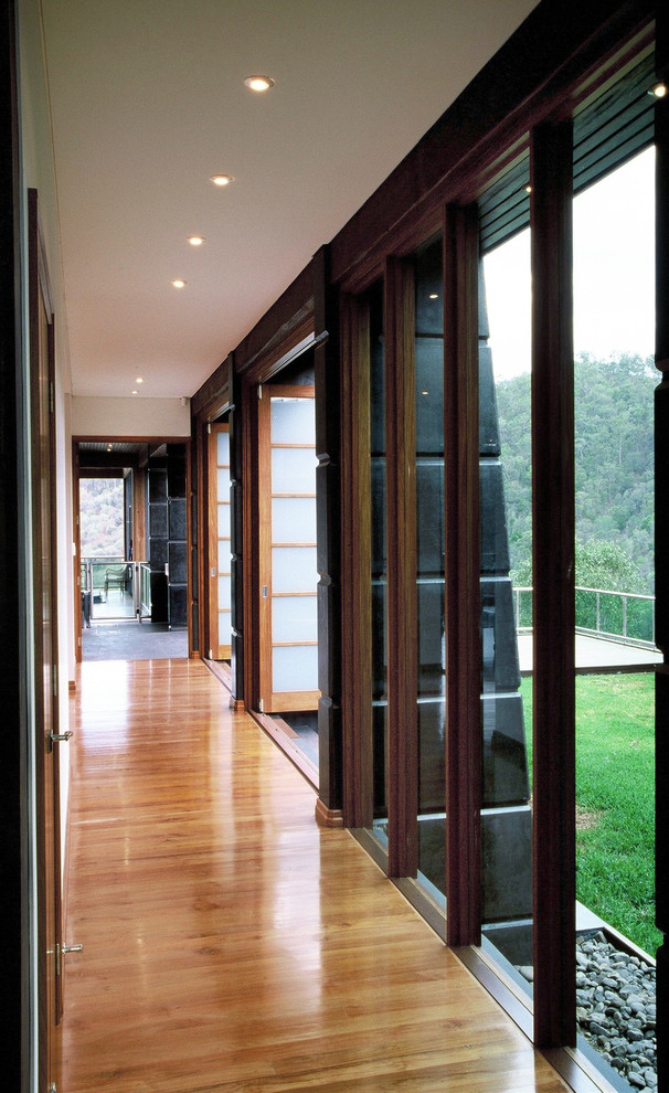 Example of a huge medium tone wood floor and brown floor hallway design in Brisbane with white walls
