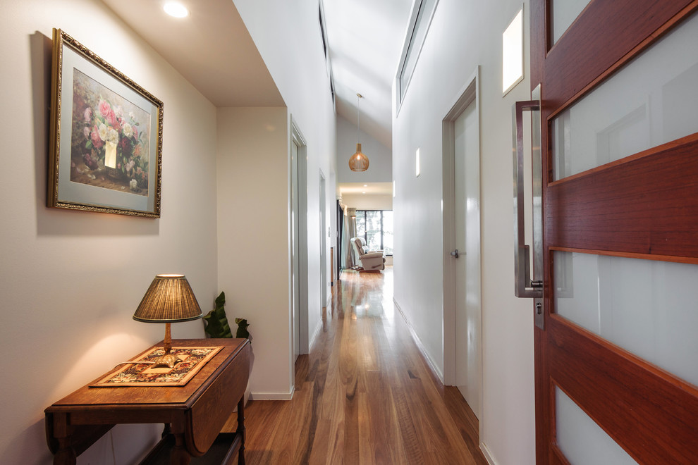 Immagine di un ingresso o corridoio design con pareti bianche e pavimento in legno massello medio